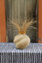 Handwoven Bolga Baobab-inspired basket in all natural straw with natural grass sprigs bursting from the top.