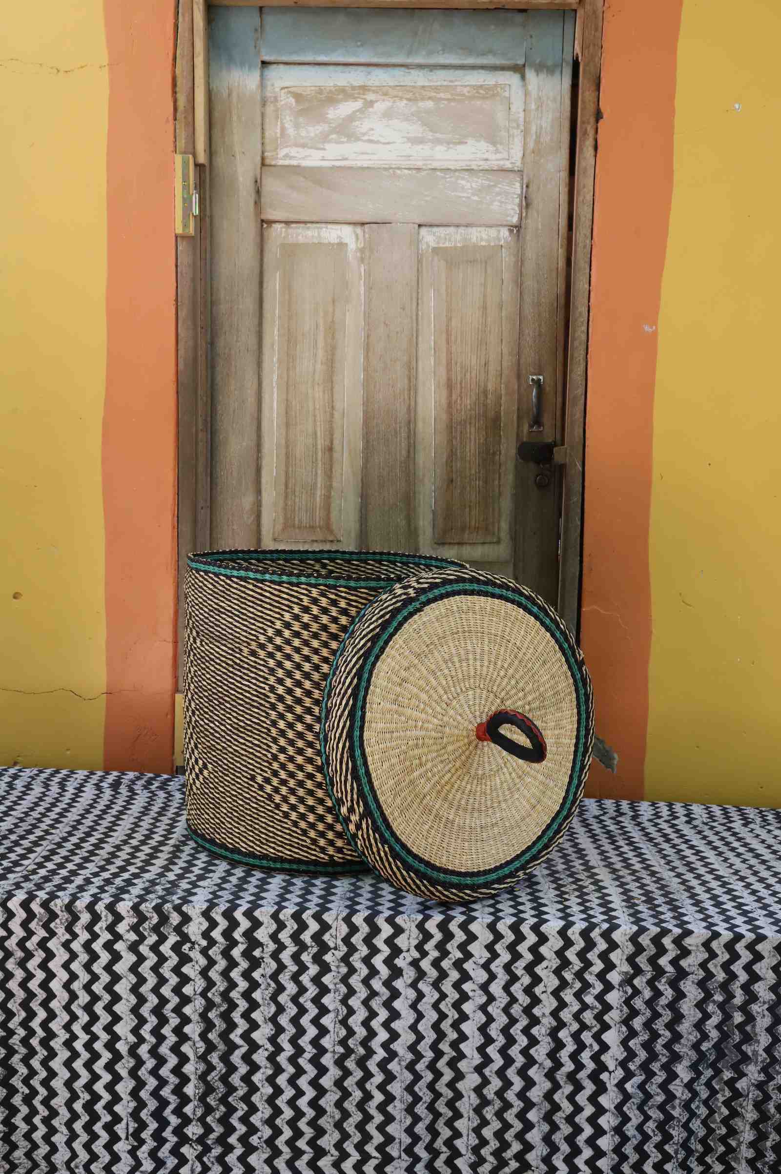 Handwoven Bolga laundry basket with lid removed, natural straw checker body with teal rim accent on the lid.