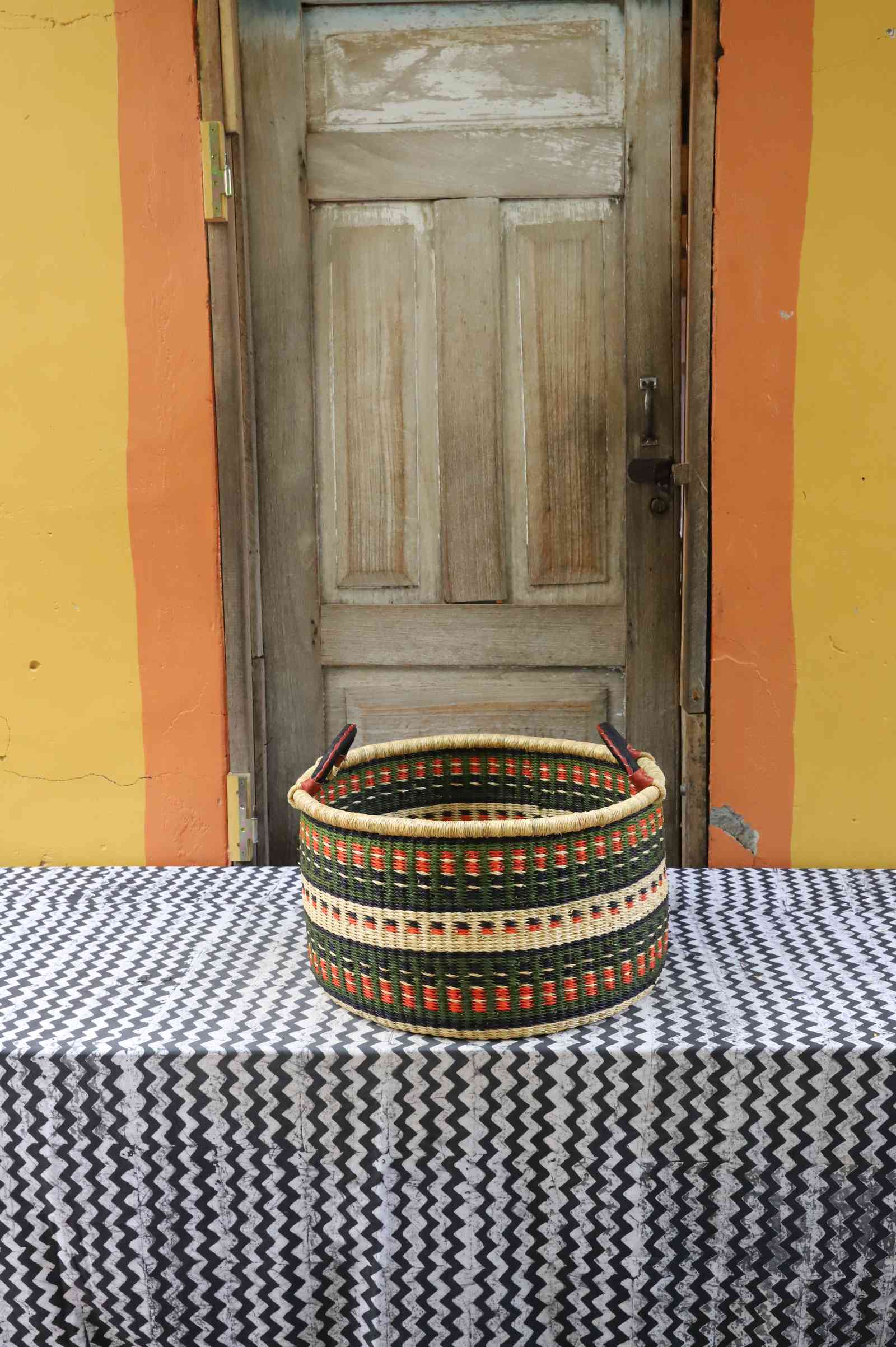 Medium handwoven Bolga storage tub in natural straw with a bold dark zigzag triangle pattern.