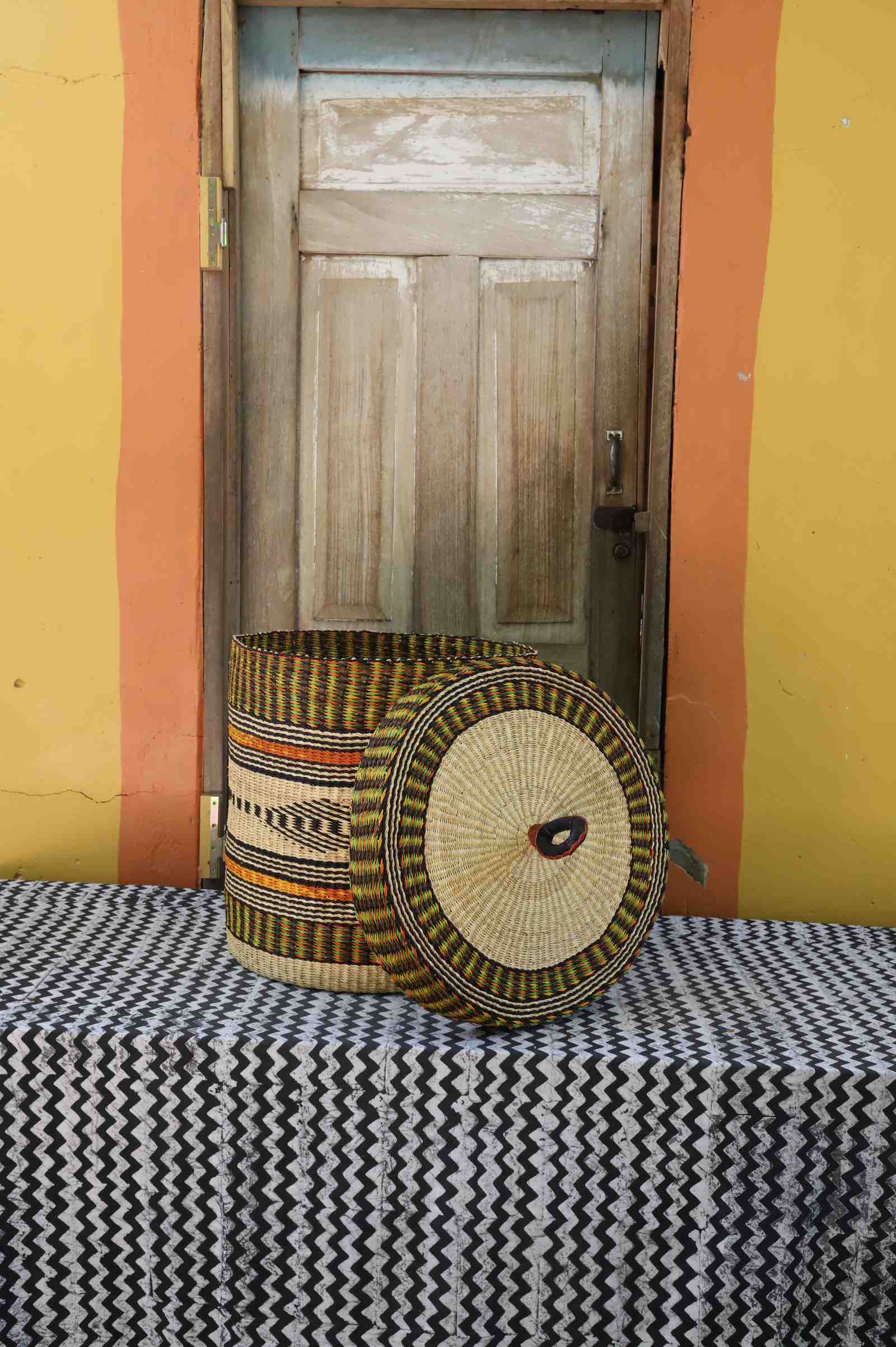 Handwoven Bolga laundry basket with lid removed, multicolour banded body and natural woven lid.