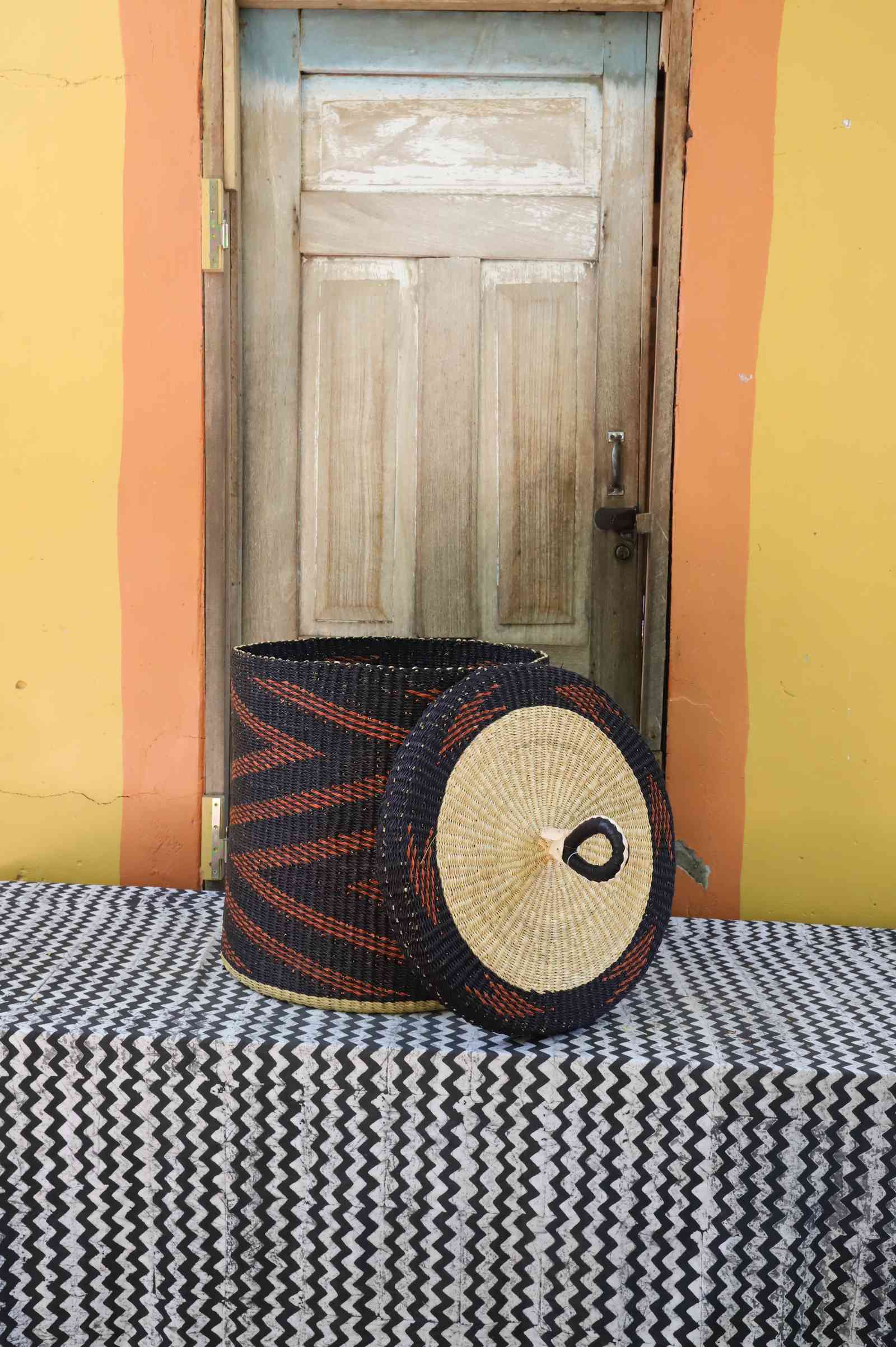 Handwoven Bolga laundry basket with lid removed, dark blue body with rust-orange zigzag pattern and lid.