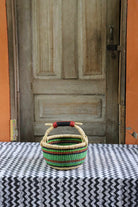 Round Bolga basket handwoven in elephant grass, with a tight weave and twin handles.