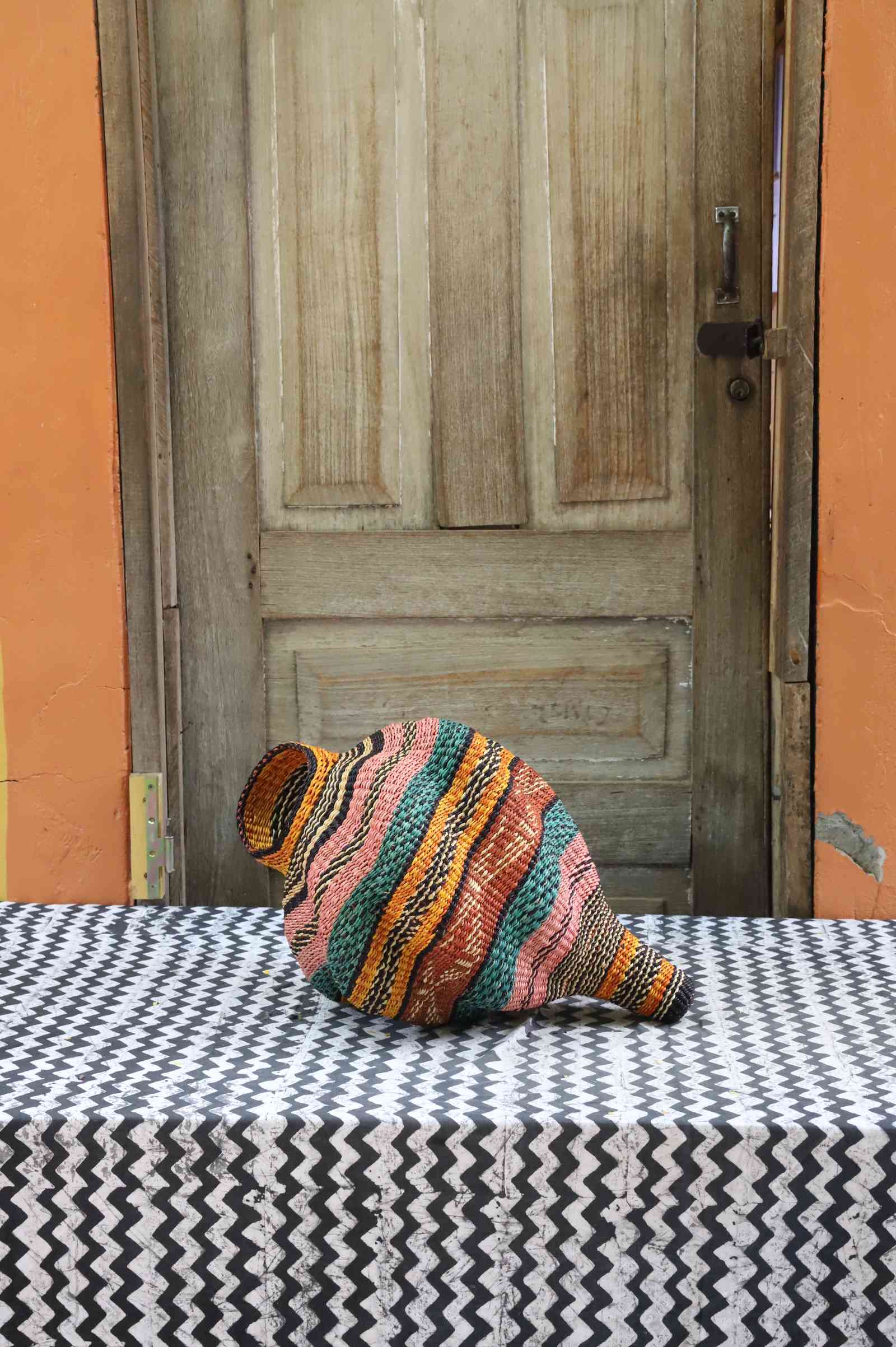 Handwoven Bolga art basket in a sculptural conch-shell form with multicolour woven stripes.