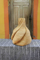 Medium handwoven Bolga art basket in a sculpted natural straw form with pinched and twisted lobes.