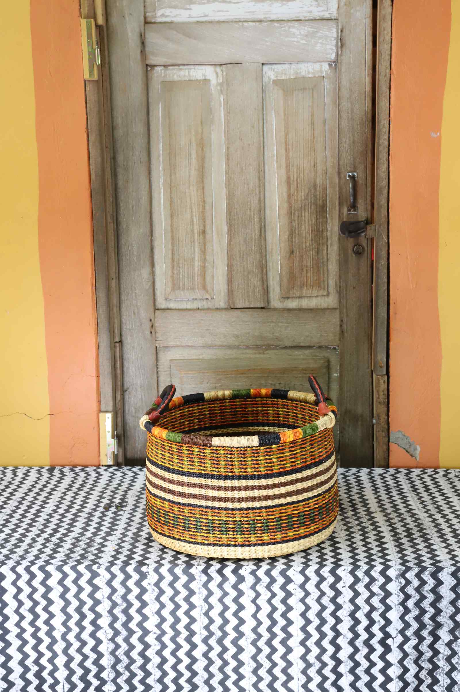 Small handwoven Bolga storage tub in natural straw with fine red banded stripes.