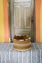 Small handwoven Bolga storage tub in natural straw with fine red banded stripes.