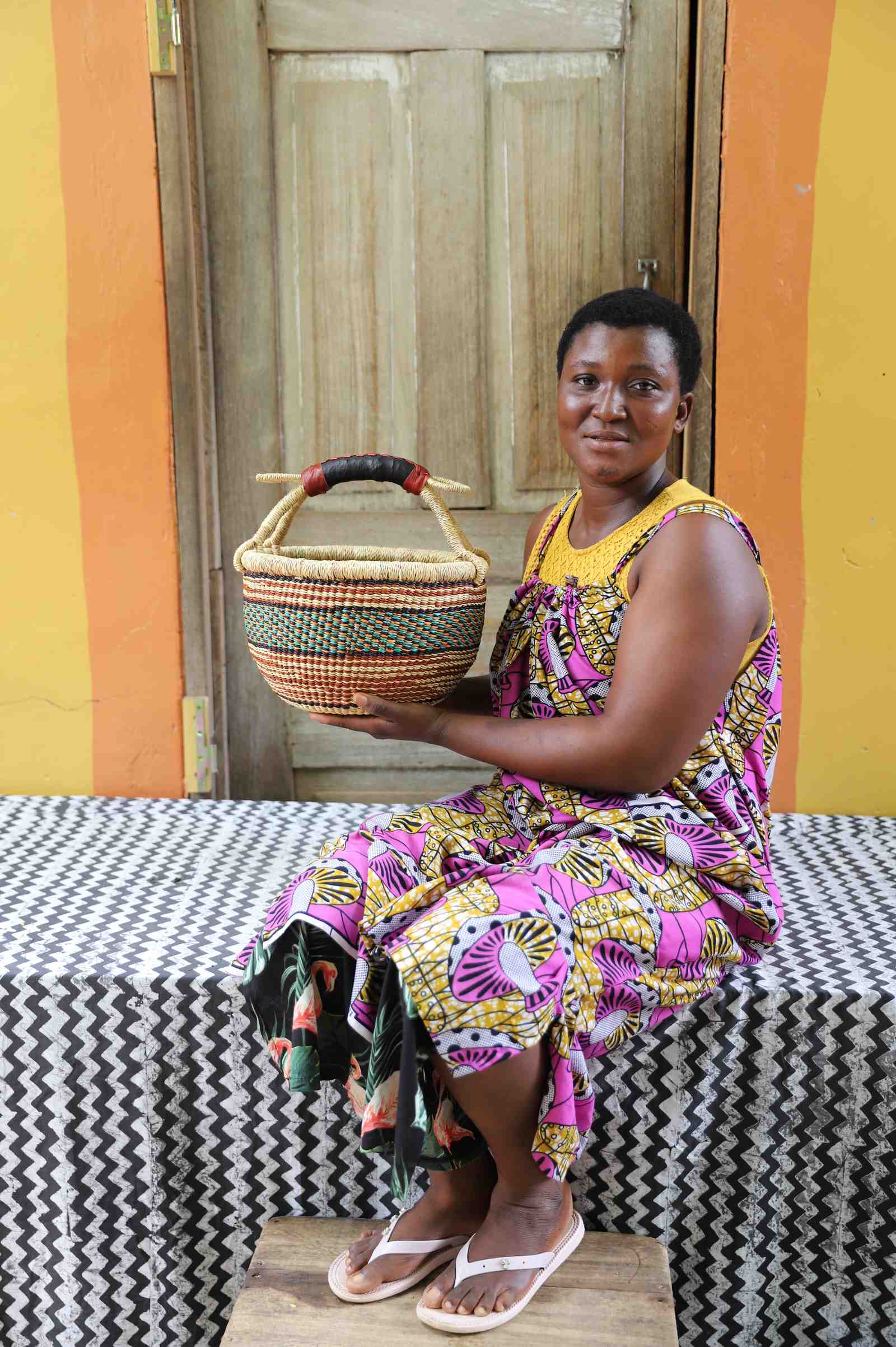 Handwoven African basket in elephant grass, round and open with two carrying handles.