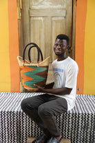 Handwoven African basket carryall in elephant grass, with two handles and a coiled rim.