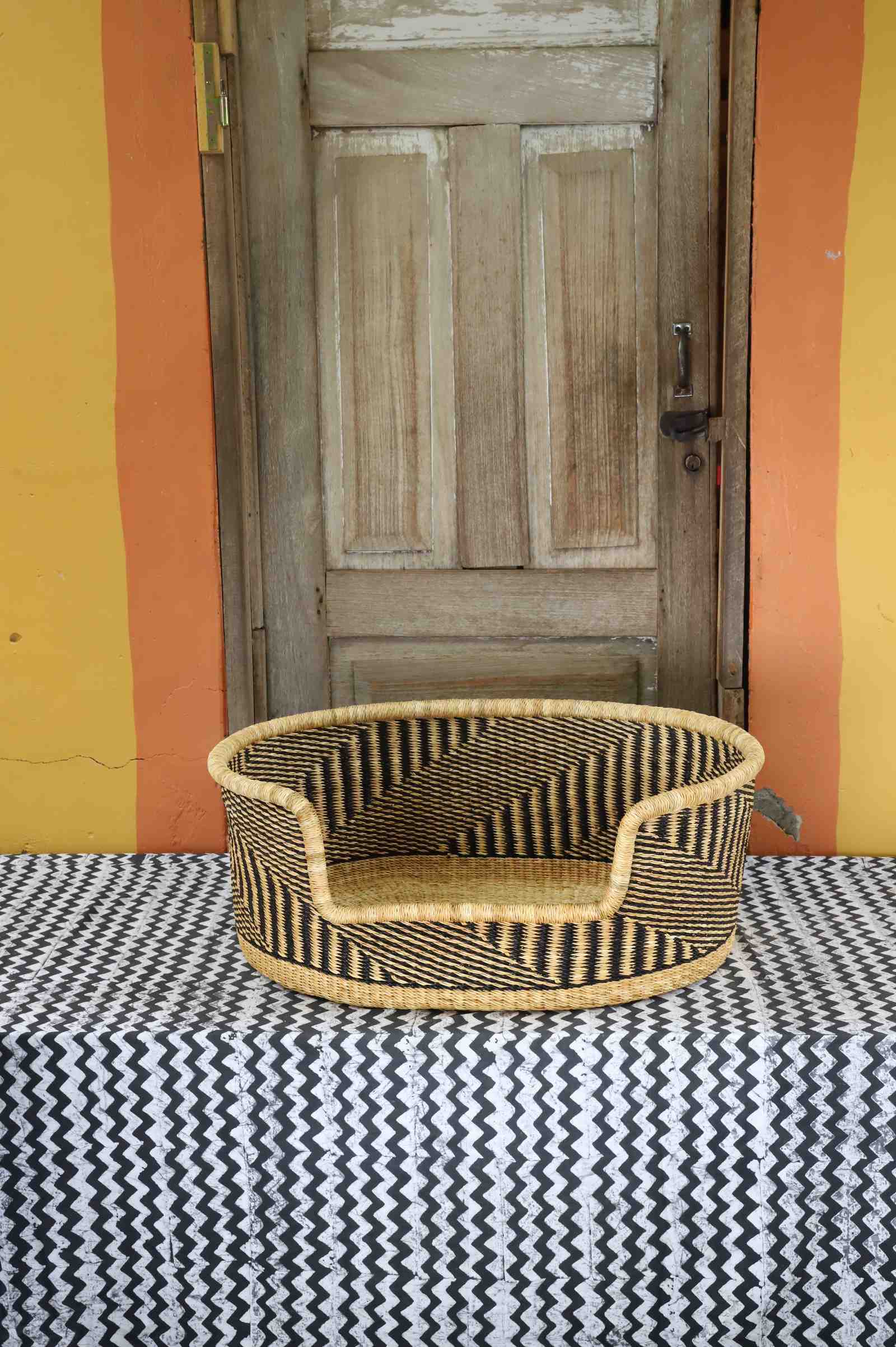 Medium handwoven Bolga pet bed in natural straw with a fine black herringbone weave pattern.