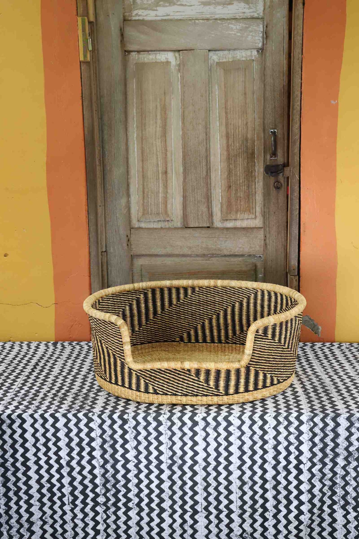 Medium handwoven Bolga pet bed in natural straw with a fine black herringbone weave pattern.