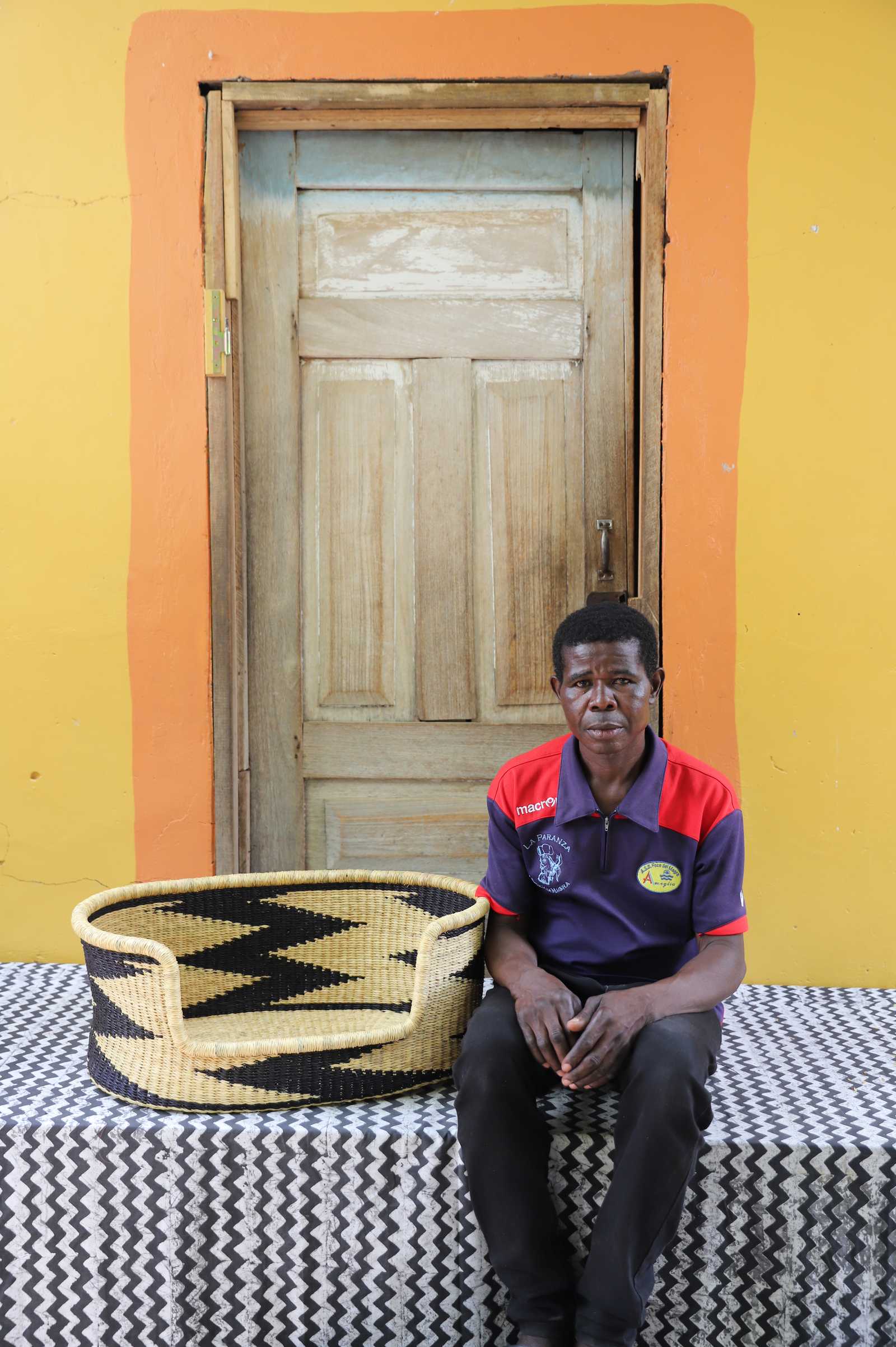 Handwoven African basket dog bed in elephant grass, with a wide low entrance.