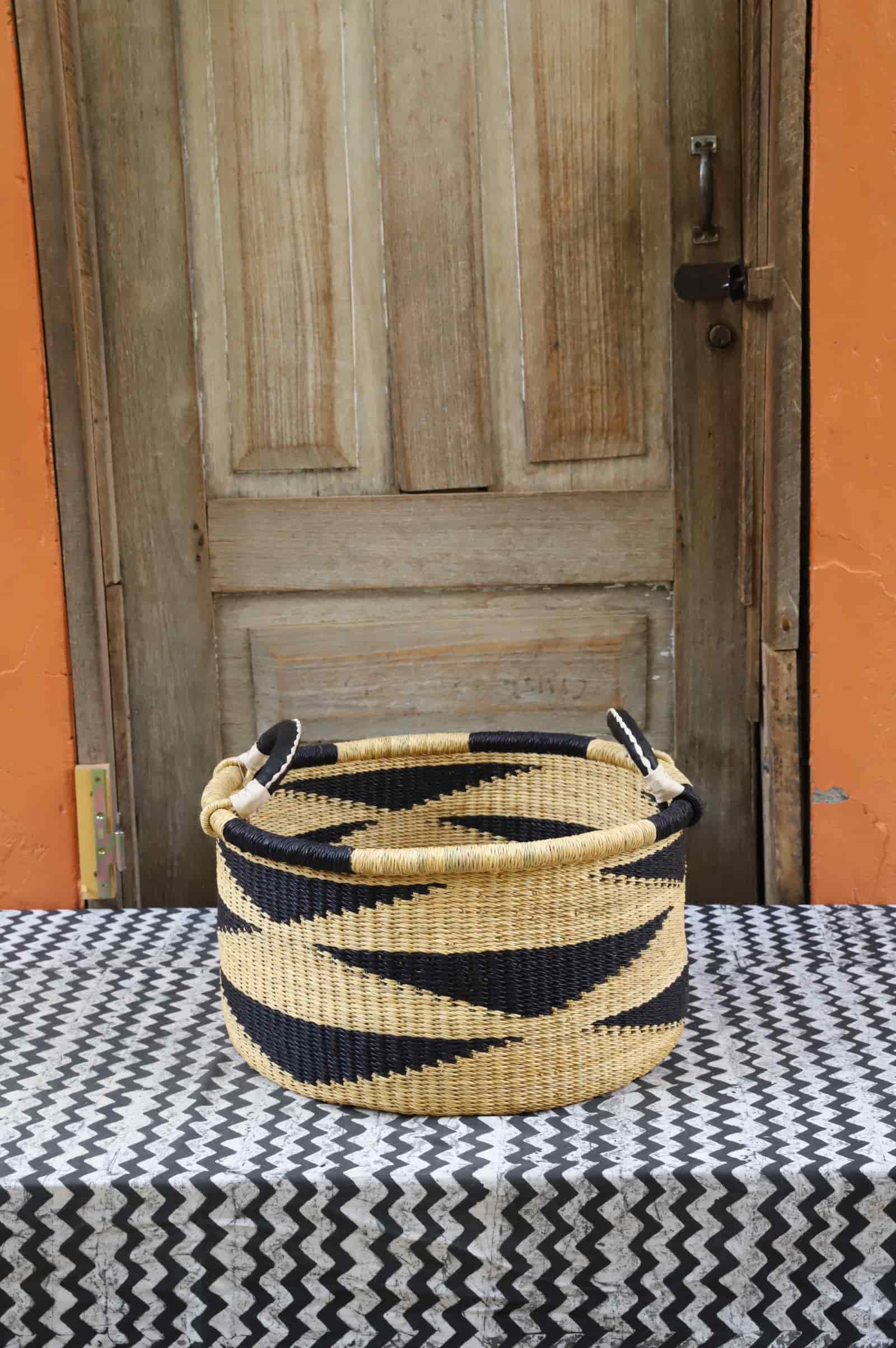 Woven Tub (Small) handwoven in Ghana sitting on black and white cloth with wooden door background